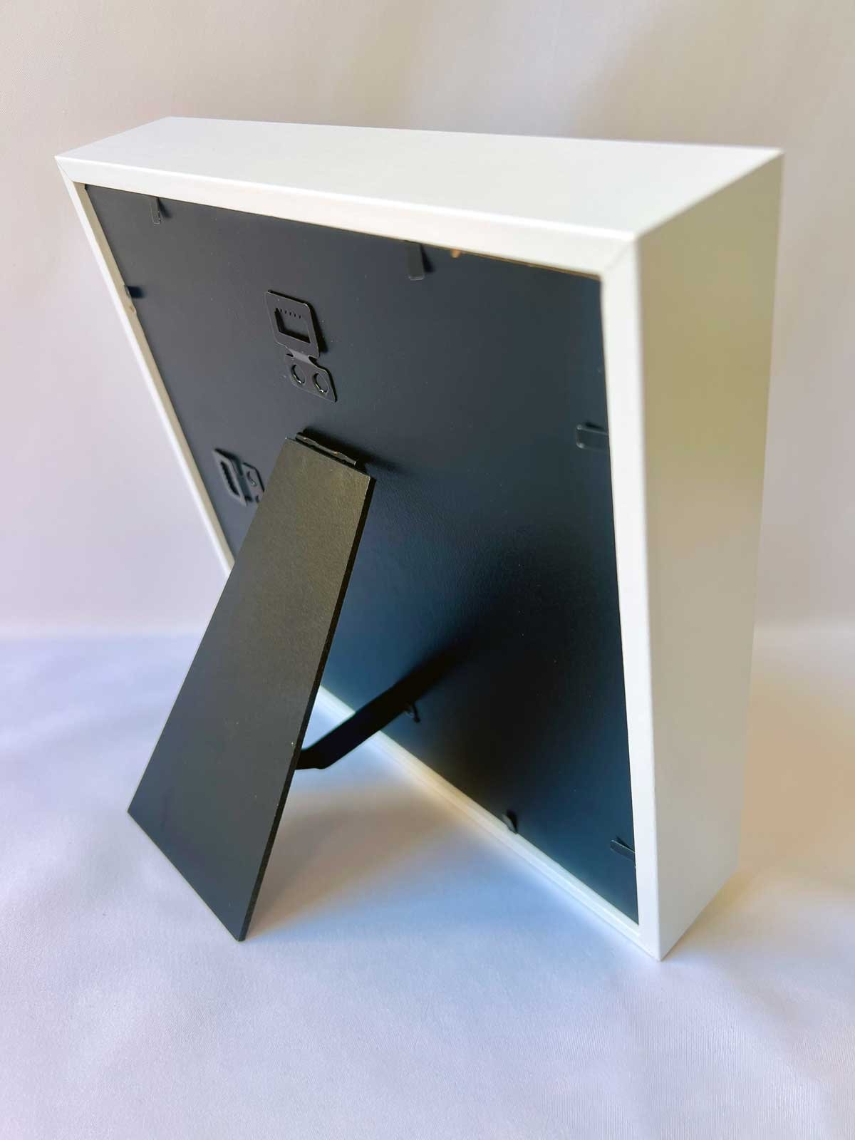 Reverso de cuadro personalizado de 22x22 cm mostrando el soporte de sobremesa y las clavijas metálicas para colgar en la pared.