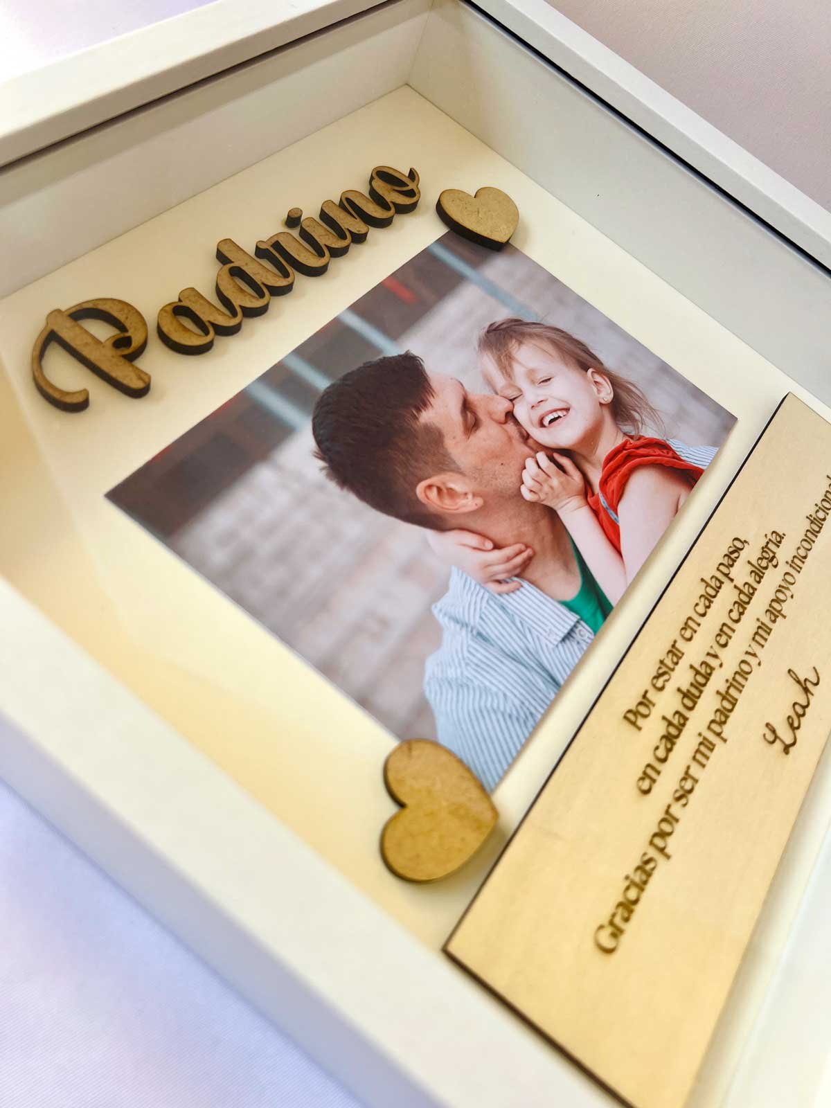 Detalle de la palabra Padrino en madera cortada a láser con relieve 3D y corazones decorativos sobre fotografía personalizada en cuadro de MomKoru.