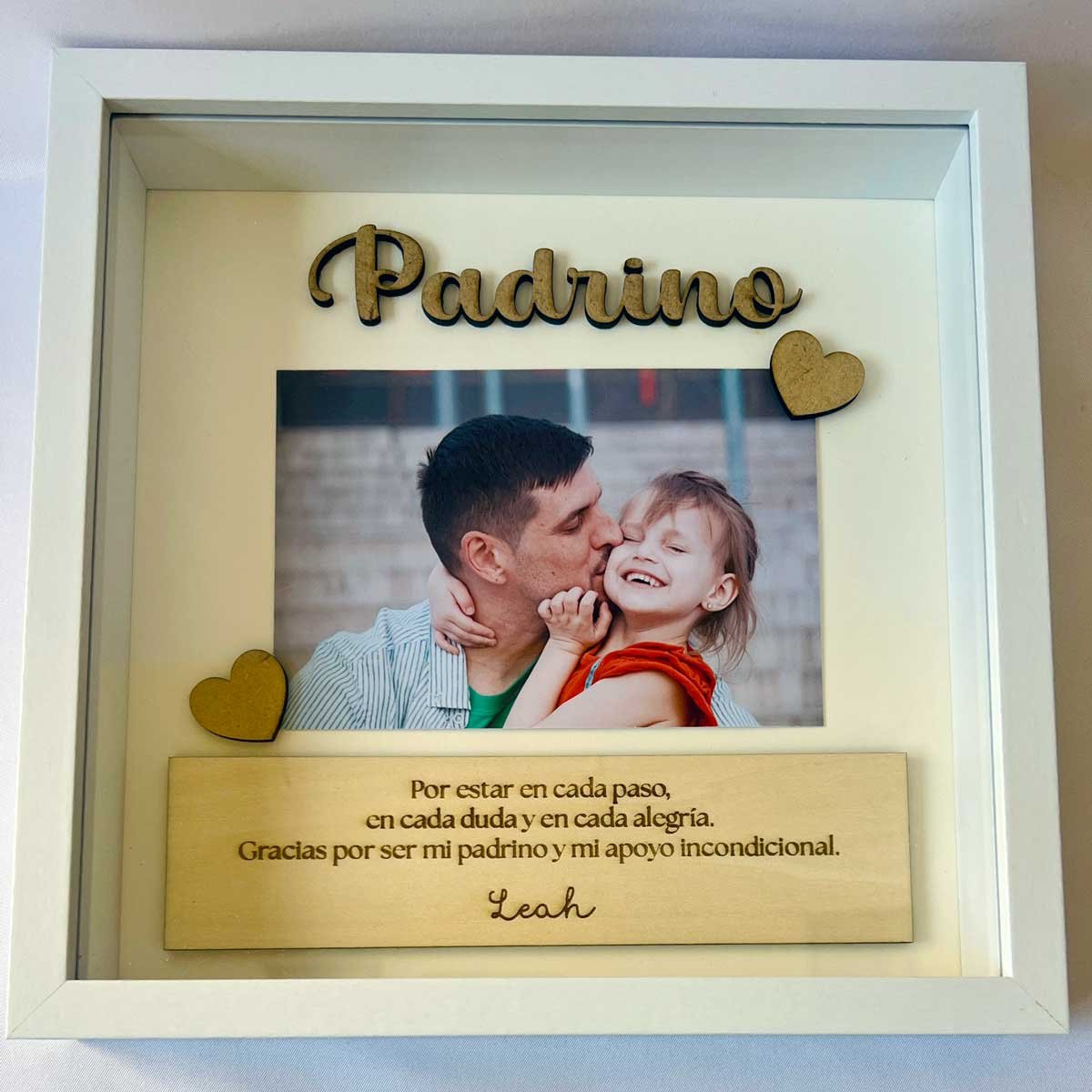 Cuadro personalizado para padrino con nombre en relieve de madera, fotografía de bebé y frase de agradecimiento en marco blanco con profundidad.