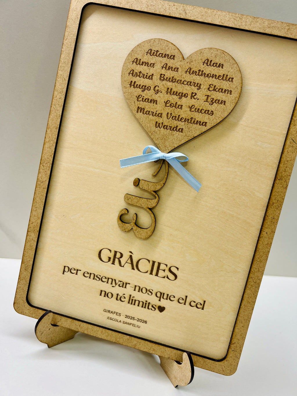 Detalle cuadro personalizado profesora madera con dedicatoria, lacito azul y caballete trasero